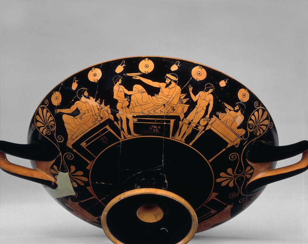 Athenian red‑figure drinking cup depicting a reclining banqueter playing kottabos