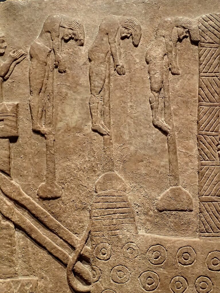 Assyrian relief showing impaled captives beneath attacking troops