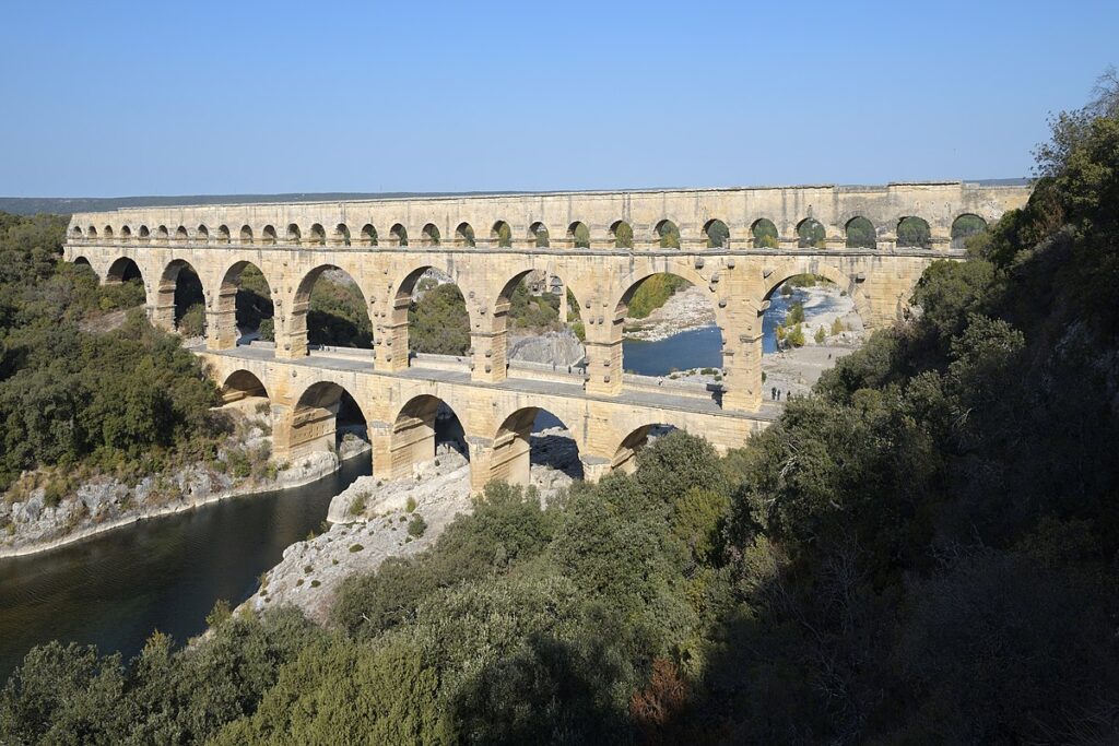 Pont du Gard aqueduct spanning a river with arches reflected in the water