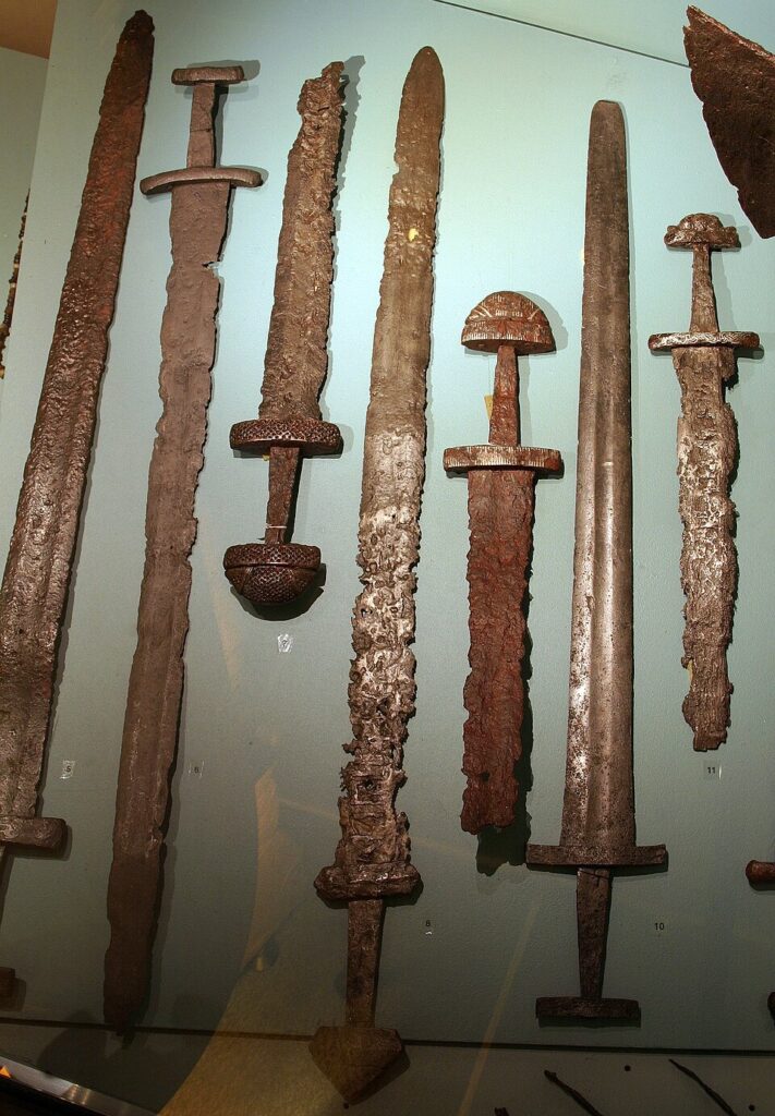 A museum case displaying Viking swords, illustrating the craftsmanship and status implied by weapon burials.