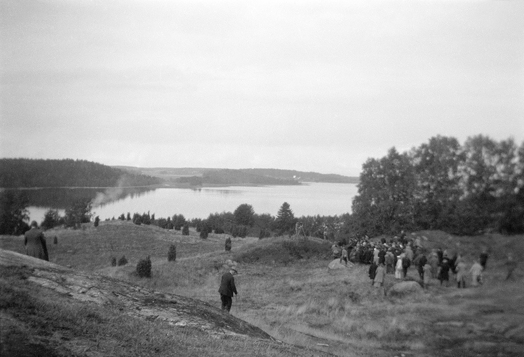 Modern visitors walking the Birka site on Björkö island, with low earthworks and signposts marking Viking Age features.